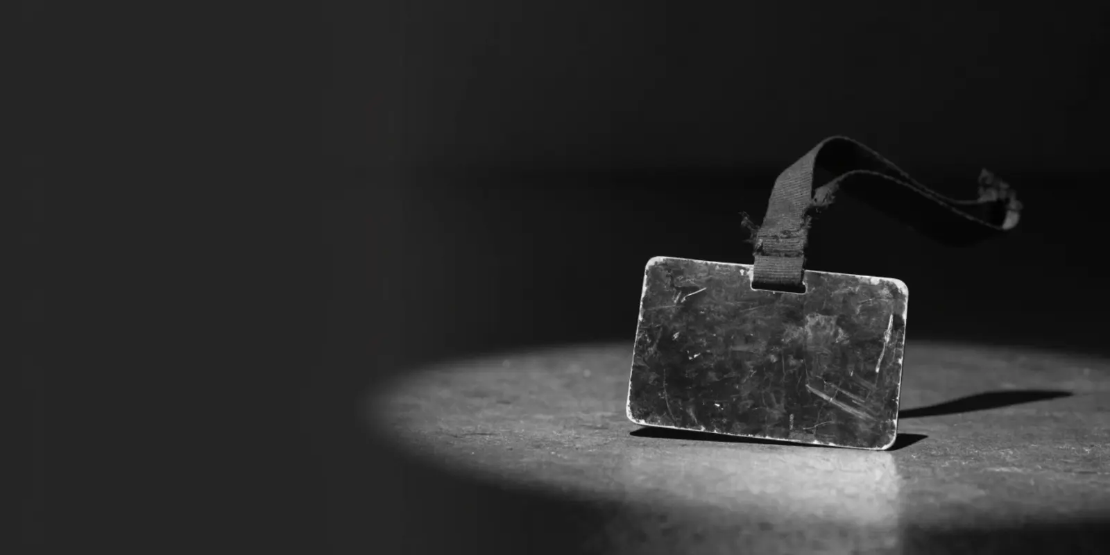 Zwart-wit foto van een oude personeelspas met kapotte lanyard, symbool voor gegevens van oud-medewerkers